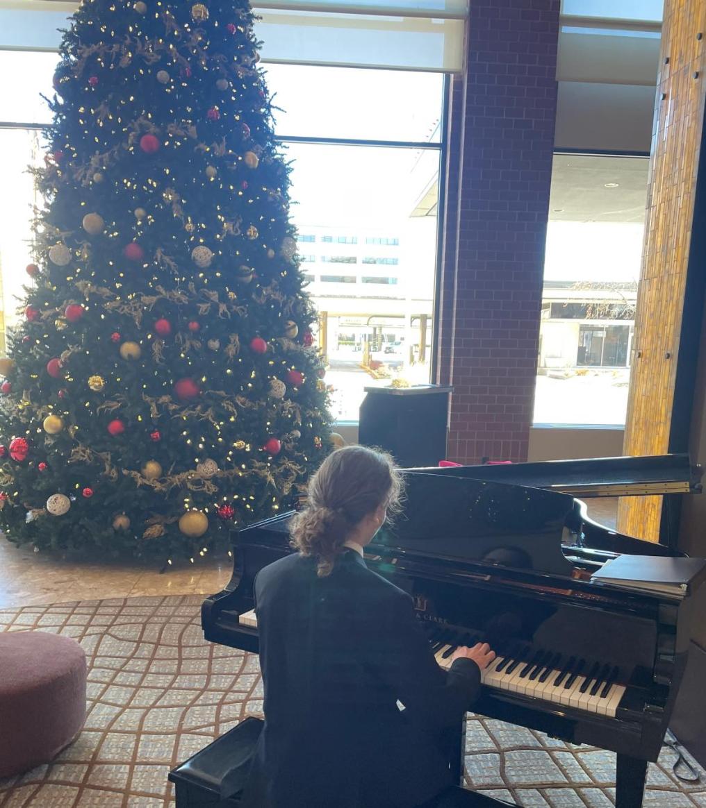 Student Playing a piano in front of a christmas tree